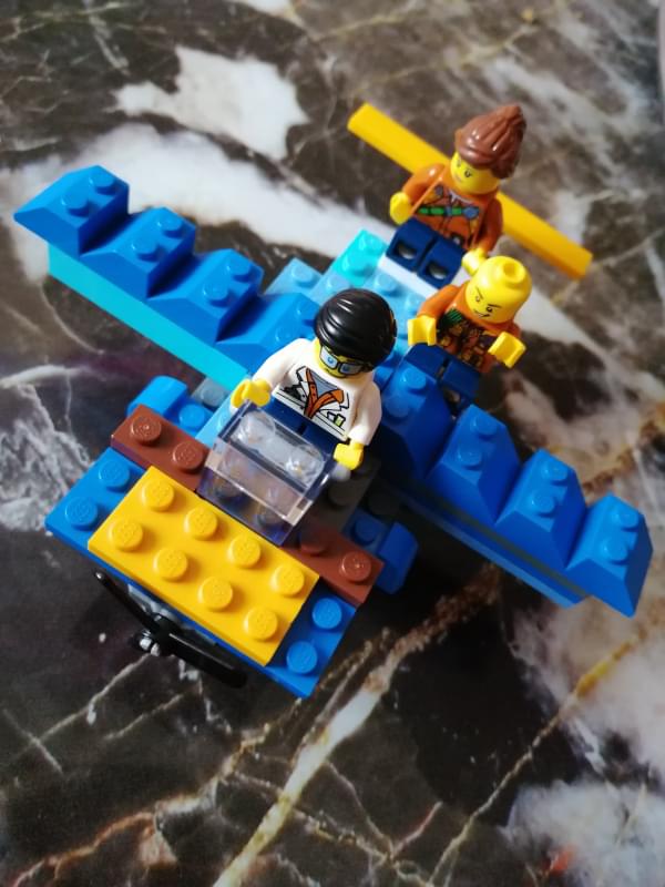 A blue aeroplane made of Lego with three minifig passengers